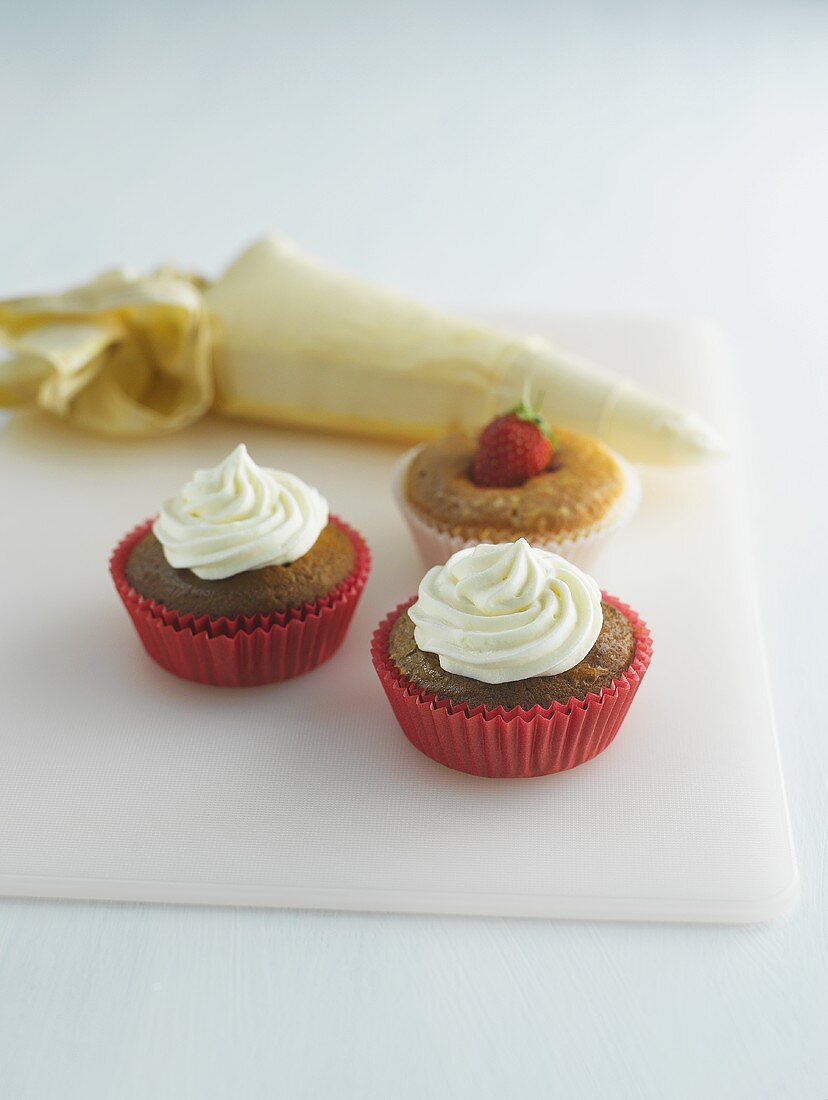 Muffins decorated with cream and strawberries