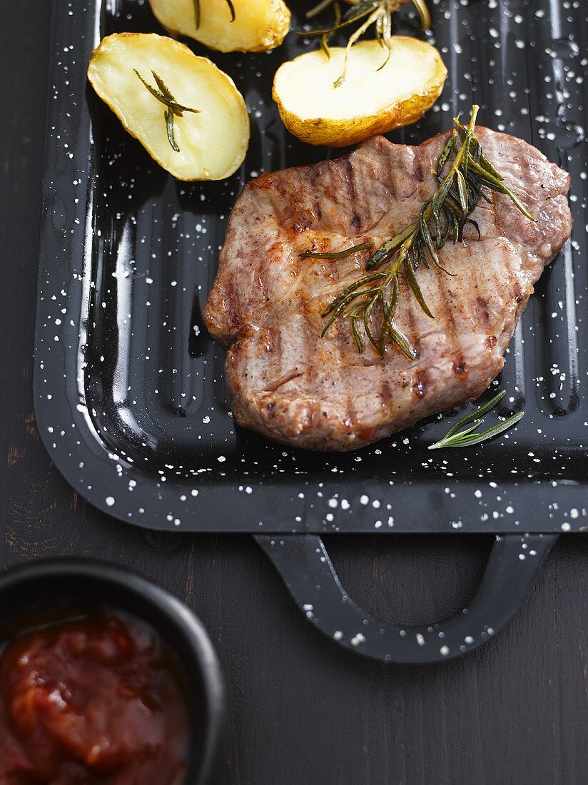 A grilled steak with rosemary, potatoes and barbeque sauce