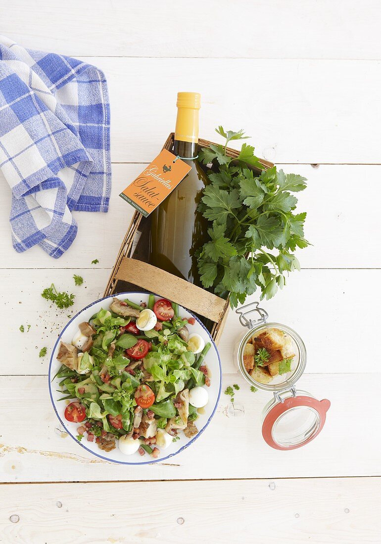 Vegetable salad, bottles of dressing and parsley in a basket