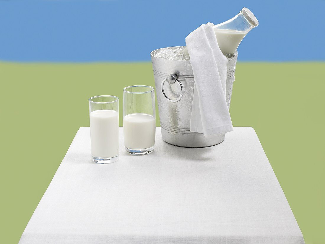 Glasses of milk and a bottle of milk in an ice bucket