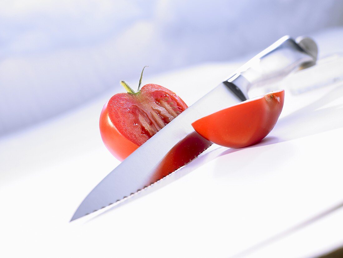 Halbierte Tomate mit Küchenmesser