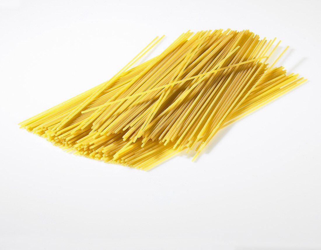 Uncooked spaghetti on a white surface