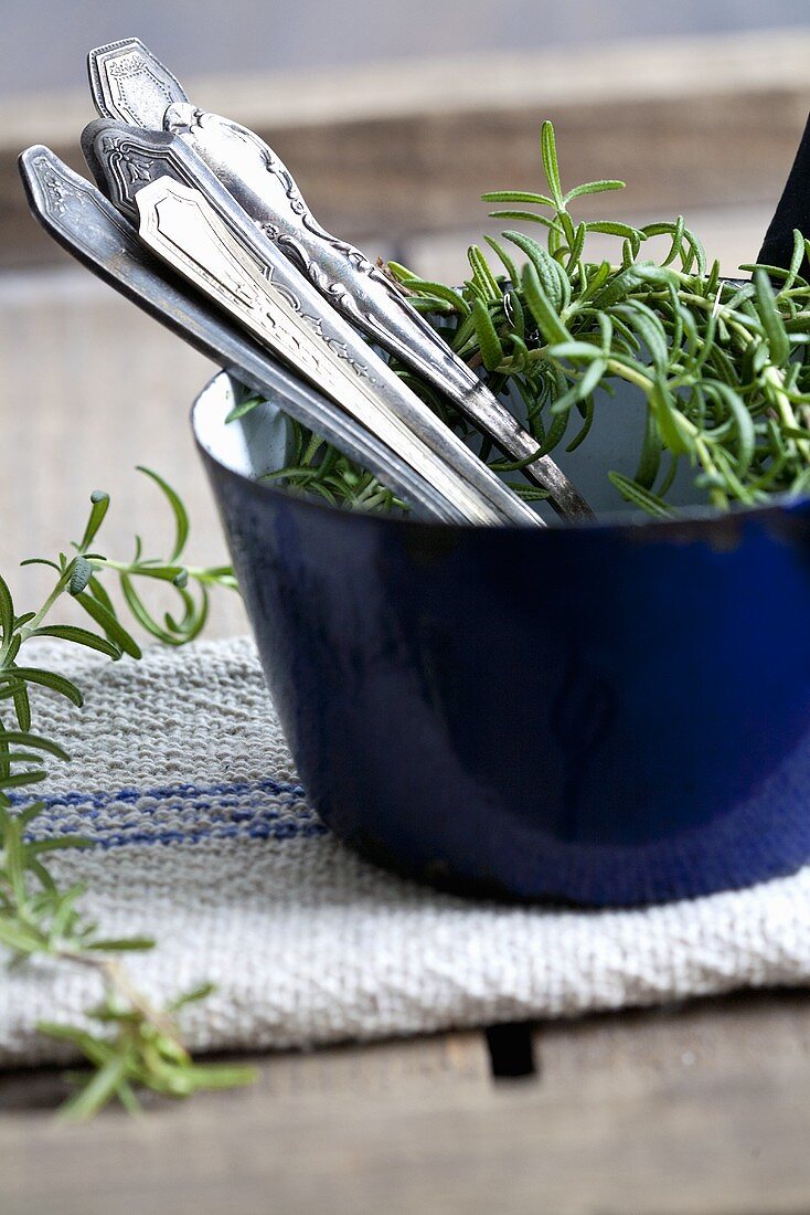 Cutlery and rosemary in a pot