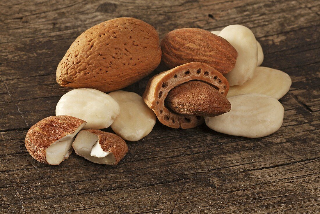 Almonds with and without shells on a wooden surface