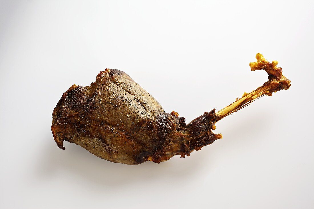 A roasted leg of venison on a white wooden surface