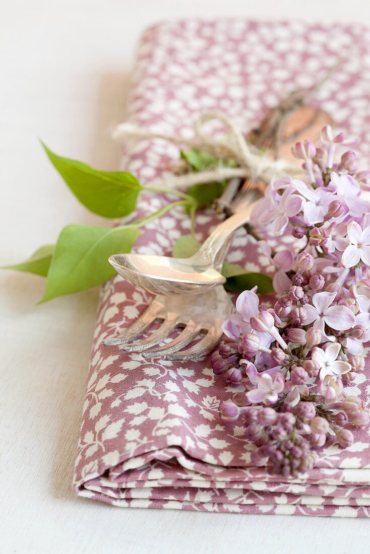 A napkin, cutlery and lilac