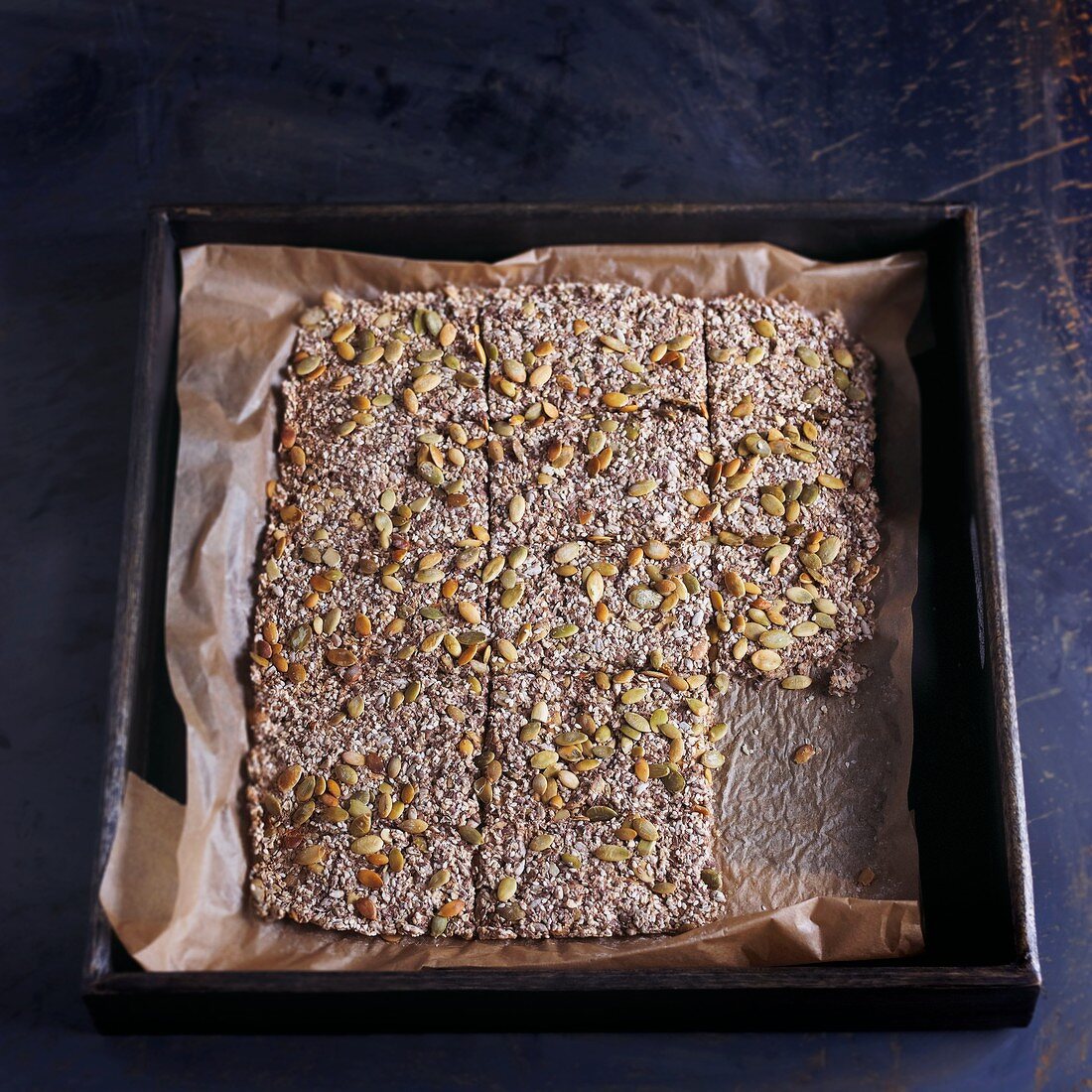 Selbstgemachte Vollkorncracker mit Kernen auf dem Backblech