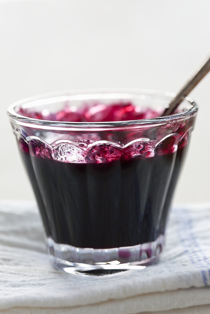 Blueberry jam in a glass bowl with a spoon