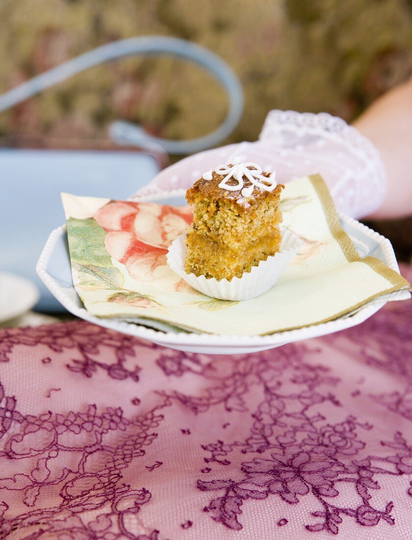 Hand holding a plate with a piece of poppy seed cake