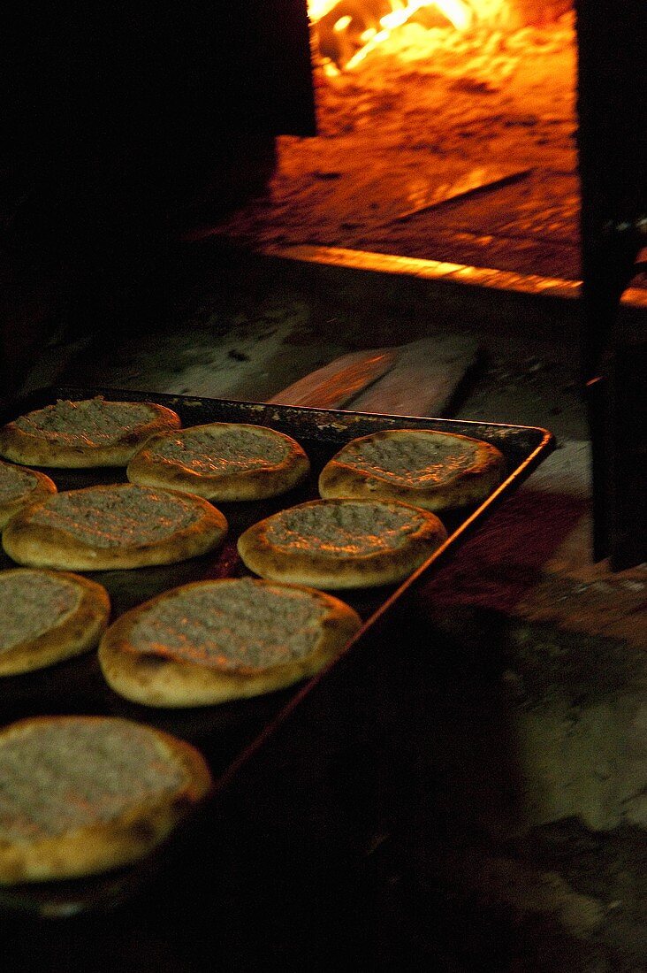A tray of unleavened bread in front of a woodfired oven