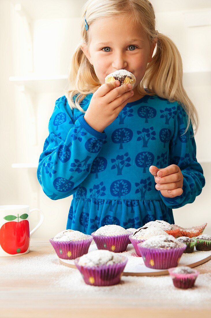A blonde girl eating a muffin