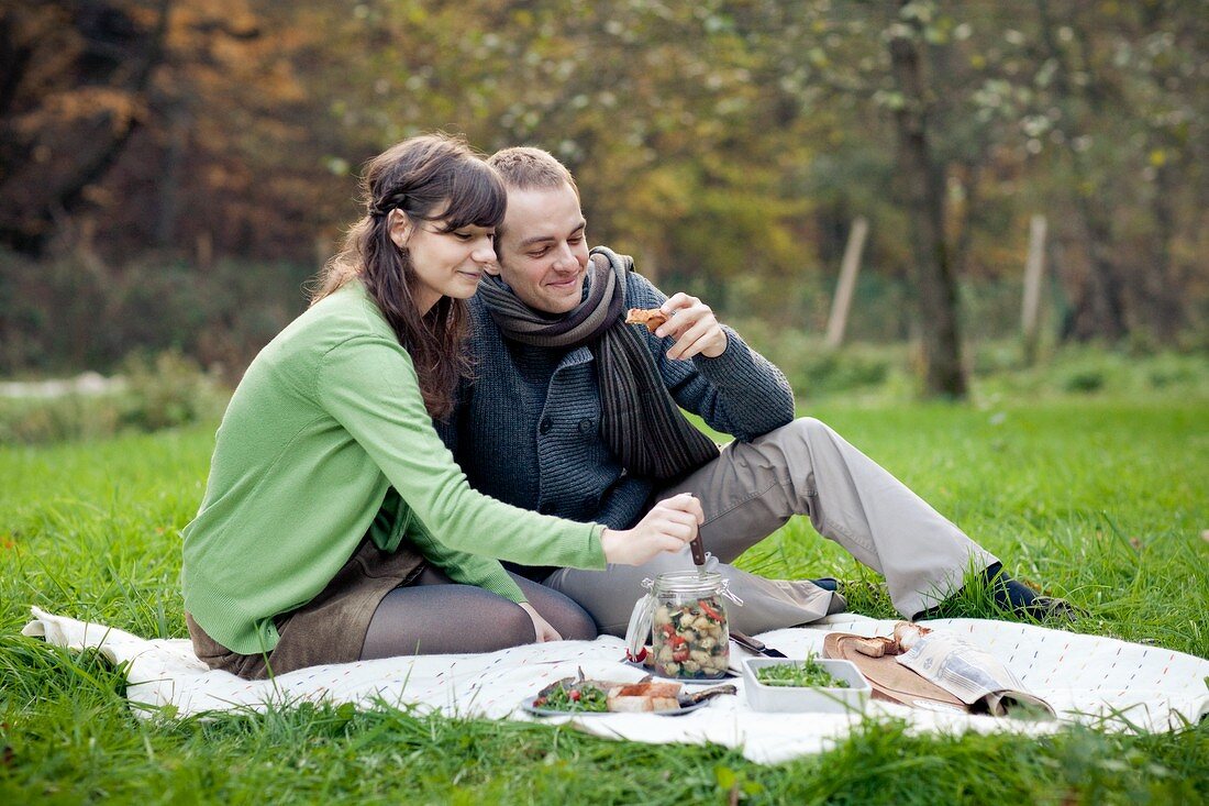 Pärchen macht Picknick auf Wiese im Herbst