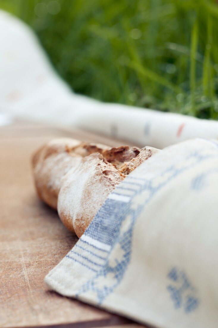 A baguette wrapped in a napkin for a picnic