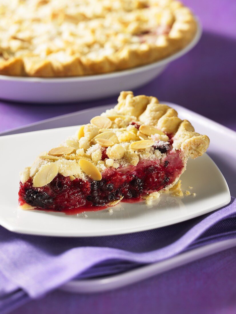 Ein Stück Brombeer-Himbeer-Streusel-Pie mit Mandelblättchen