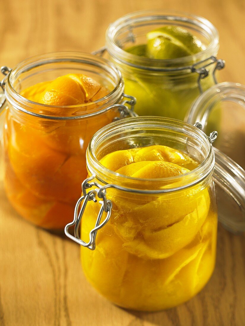 Drei geöffnete Gläser mit eingelegten Zitronen, Orangen und Limetten