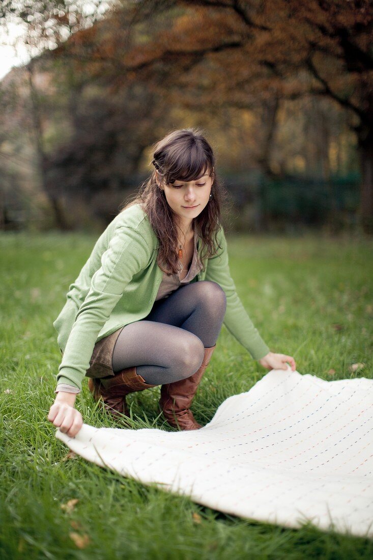 A woman spreading a picnic basket on the ground