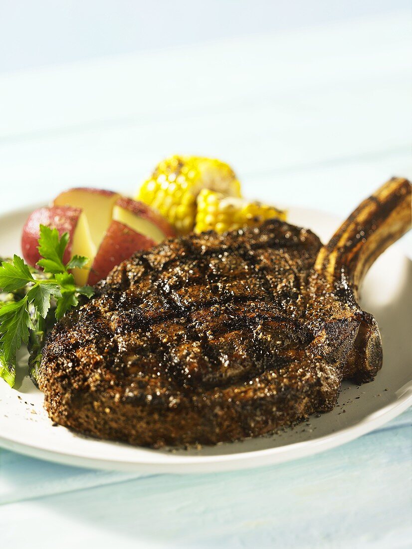 Grilled ribeye steak with potatoes and corn on the cob