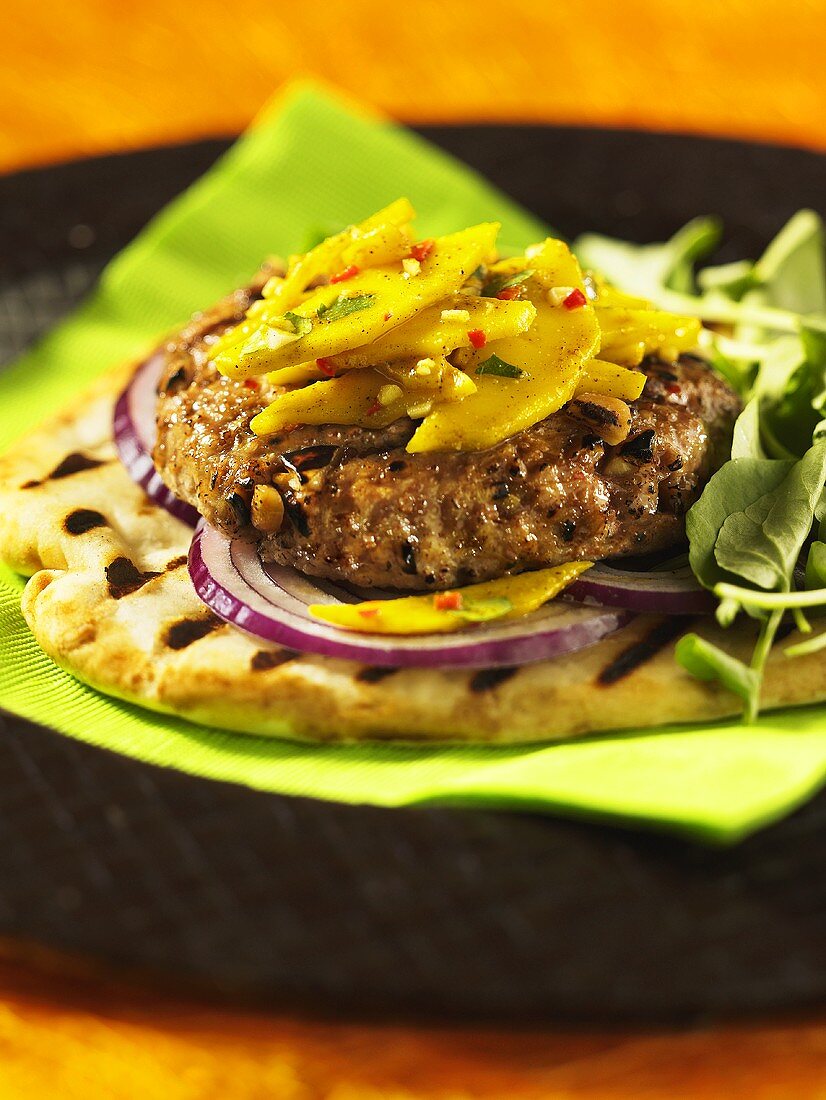 A lamb burger on flat bread with red onions and mango