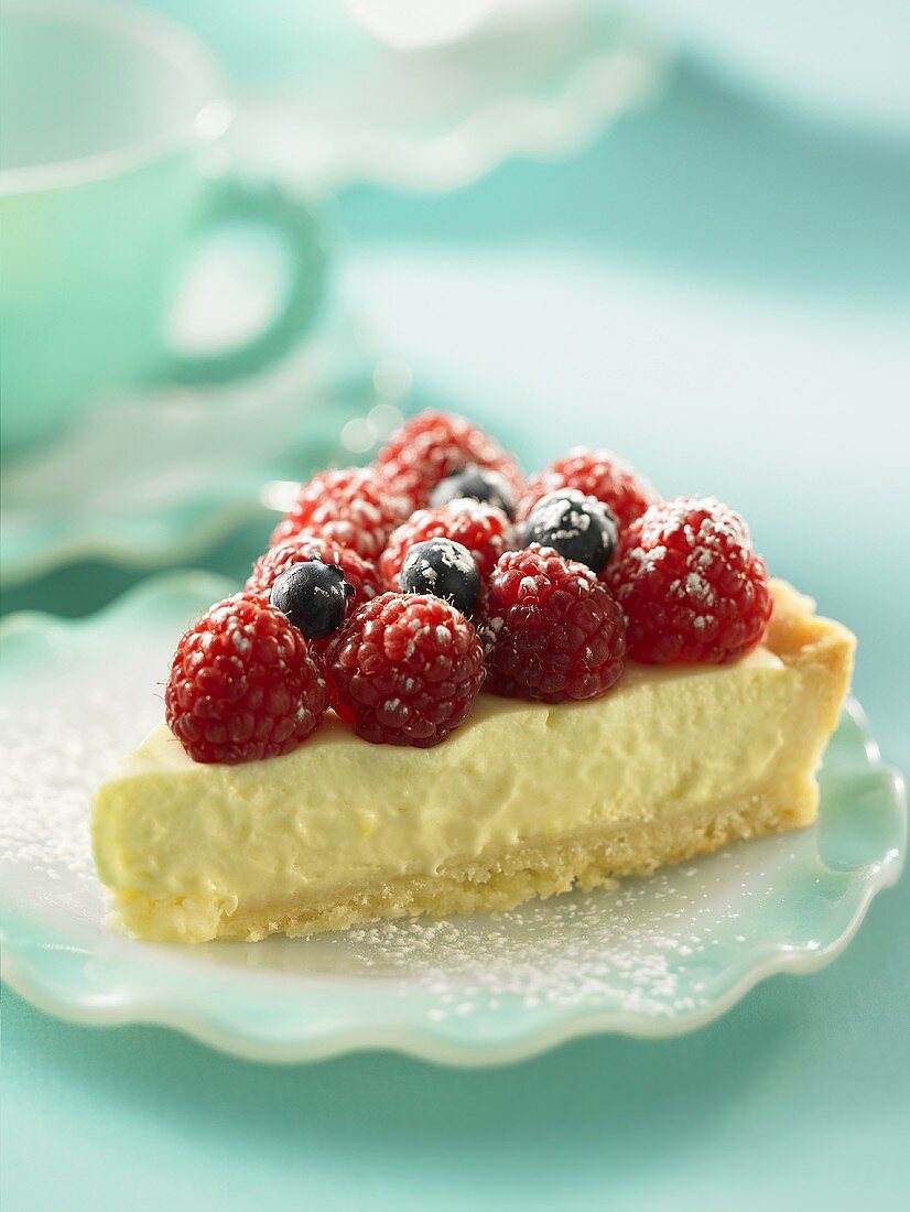 Ein Stück Käsekuchen mit Himbeeren und Heidelbeeren