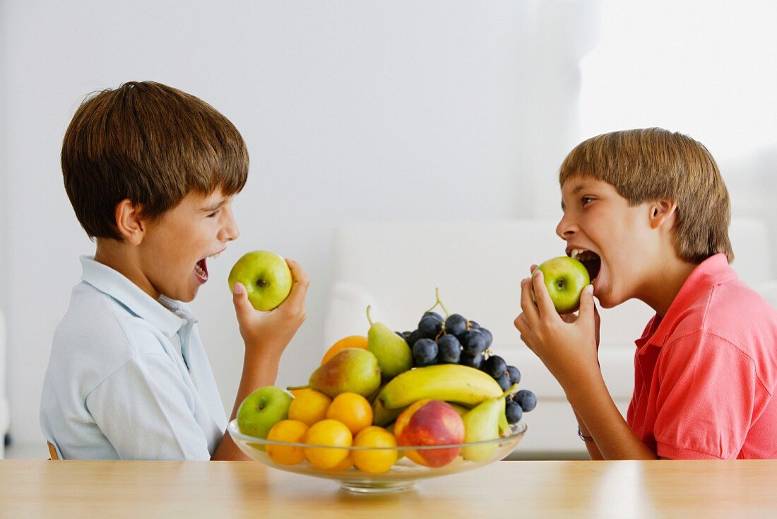Two boys biting into apples
