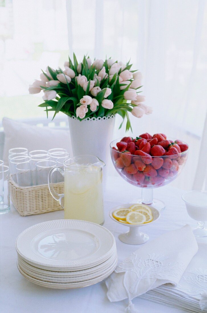 Set table with flowers, strawberries & lemonade