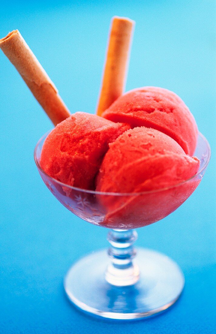 Three scoops of strawberry ice cream in a sundae glass