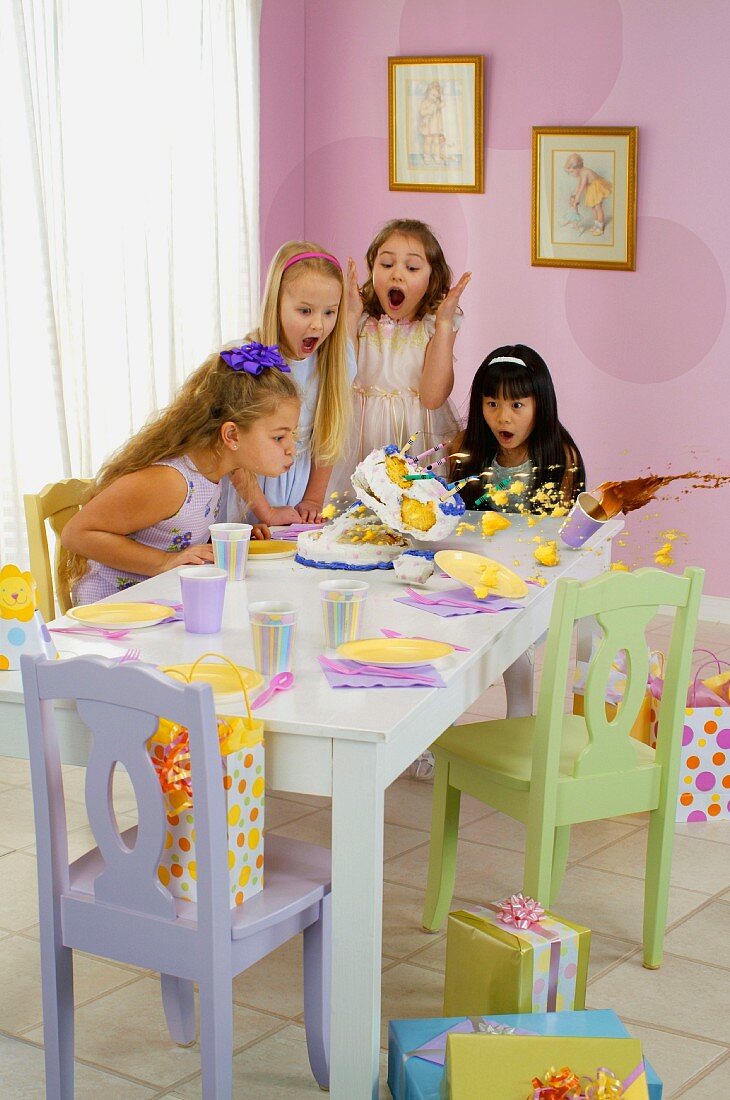 Mädchen pustet Kerzen samt Kuchen vom Tisch