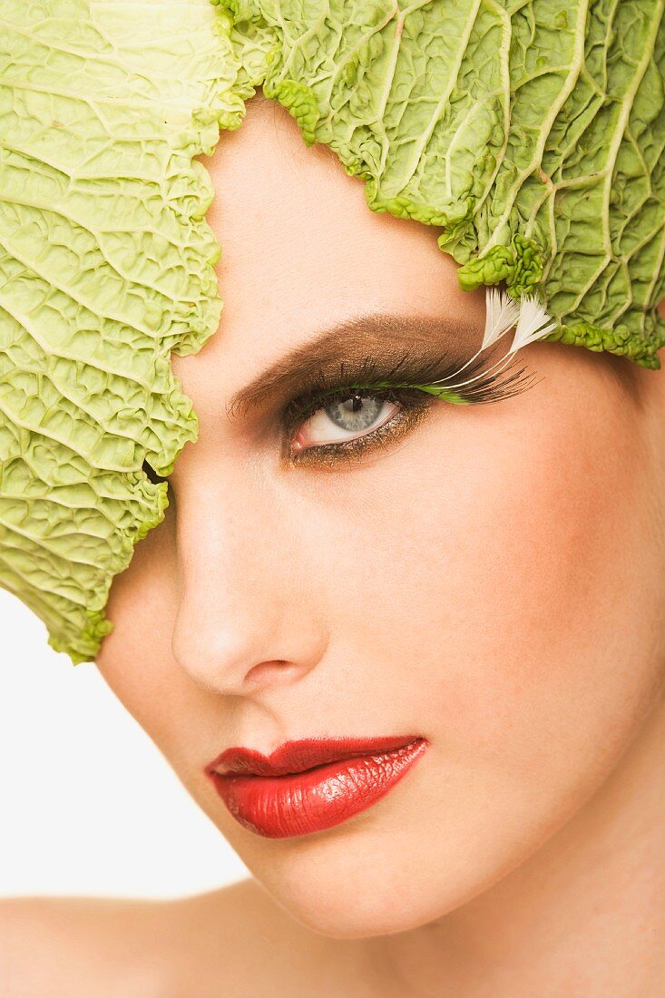 Young woman with savoy cabbage leaves on her head