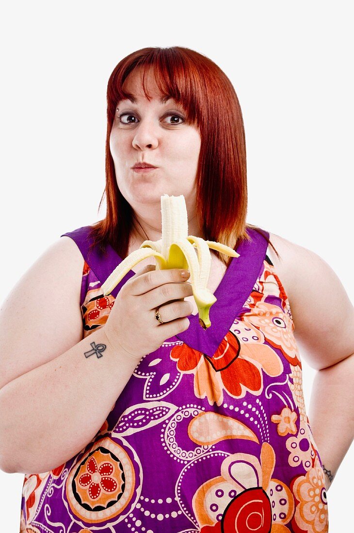 Overweight young woman eating a banana