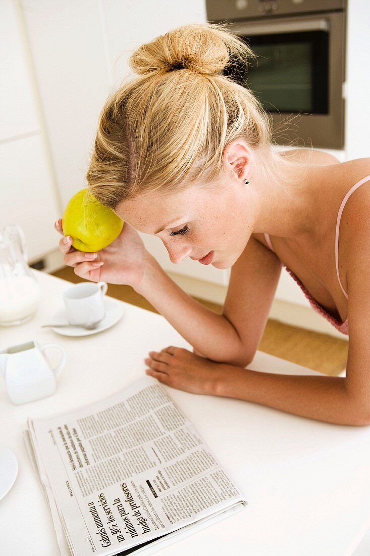 Junge Frau mit Apfel liest Zeitung