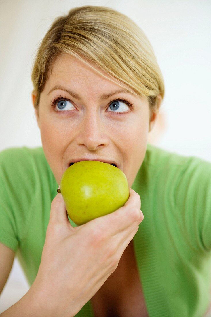 Young woman biting into an apple