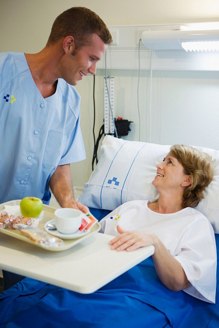 Krankenpfleger bringt der Patientin ein Tablett