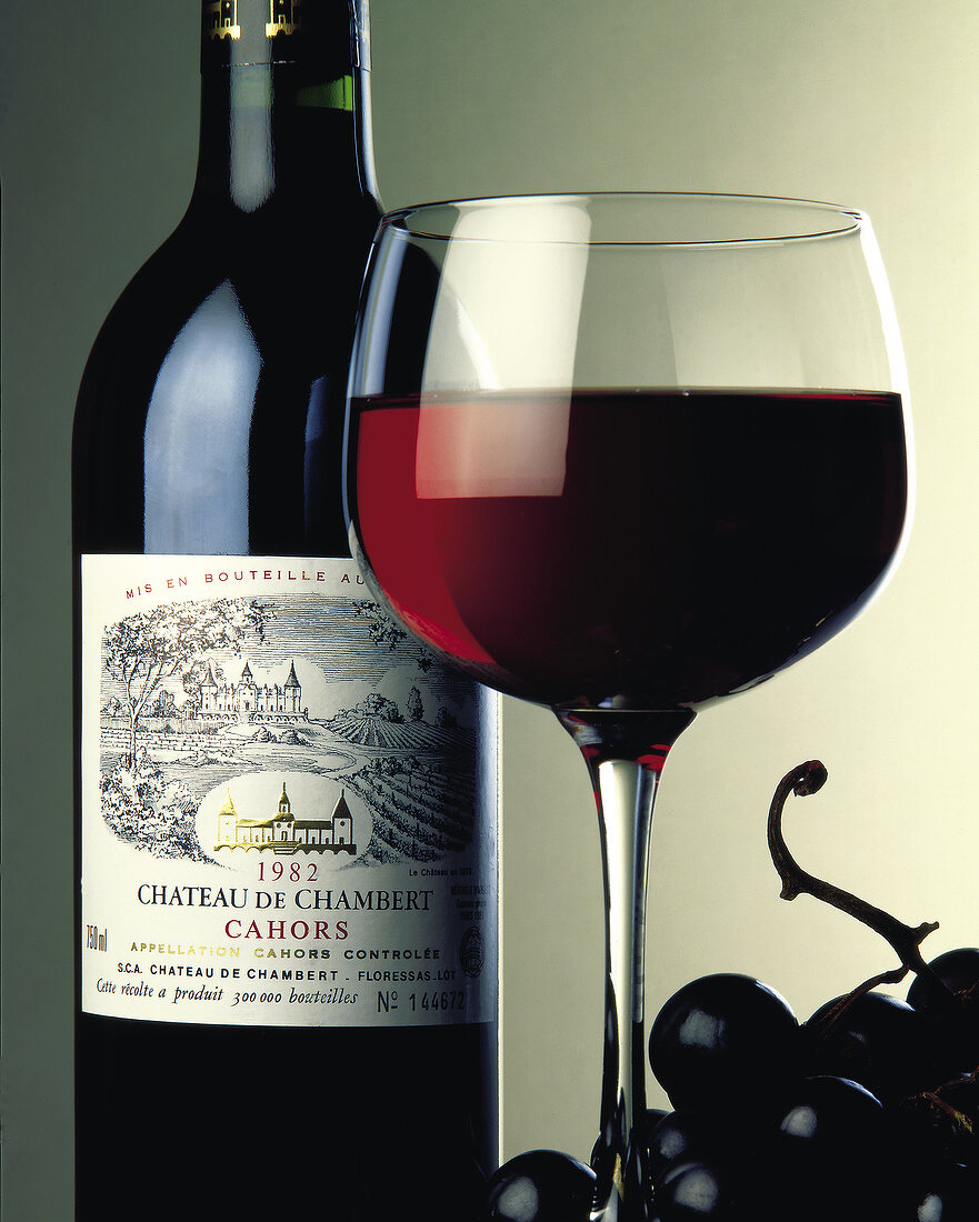Eine Flasche Rotwein, Rotwein im Glas und Weintrauben