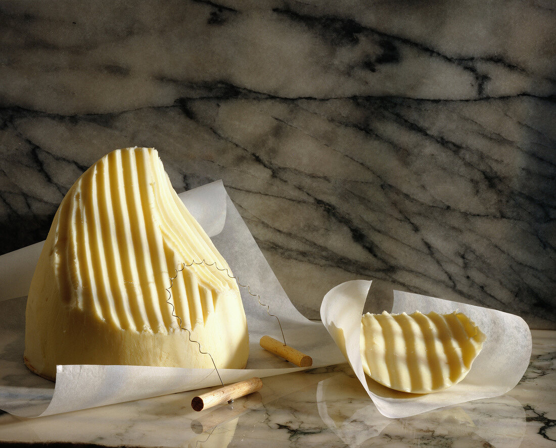 Angeschnittene Butter mit Butterschneidedraht auf Marmor