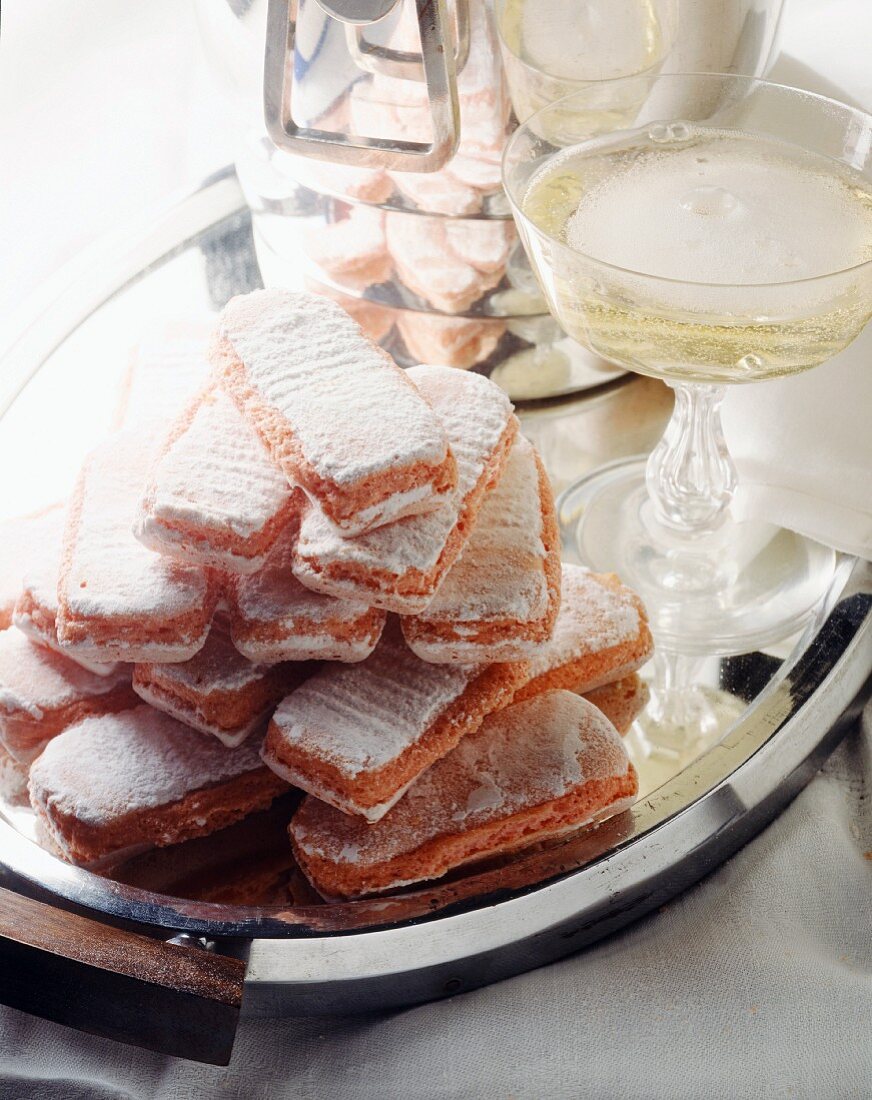 Biscuits roses de Reims (französische Biskuitkekse) mit Champagner im Glas auf einem Tablett