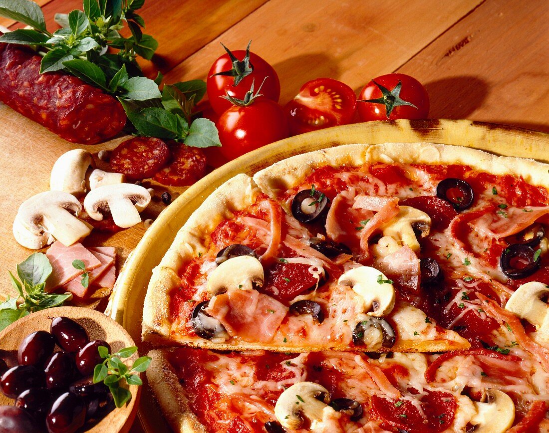 Pizza 'Regina' mit Chorizo, schwarzen Oliven, Schinken, Tomaten und Champignons