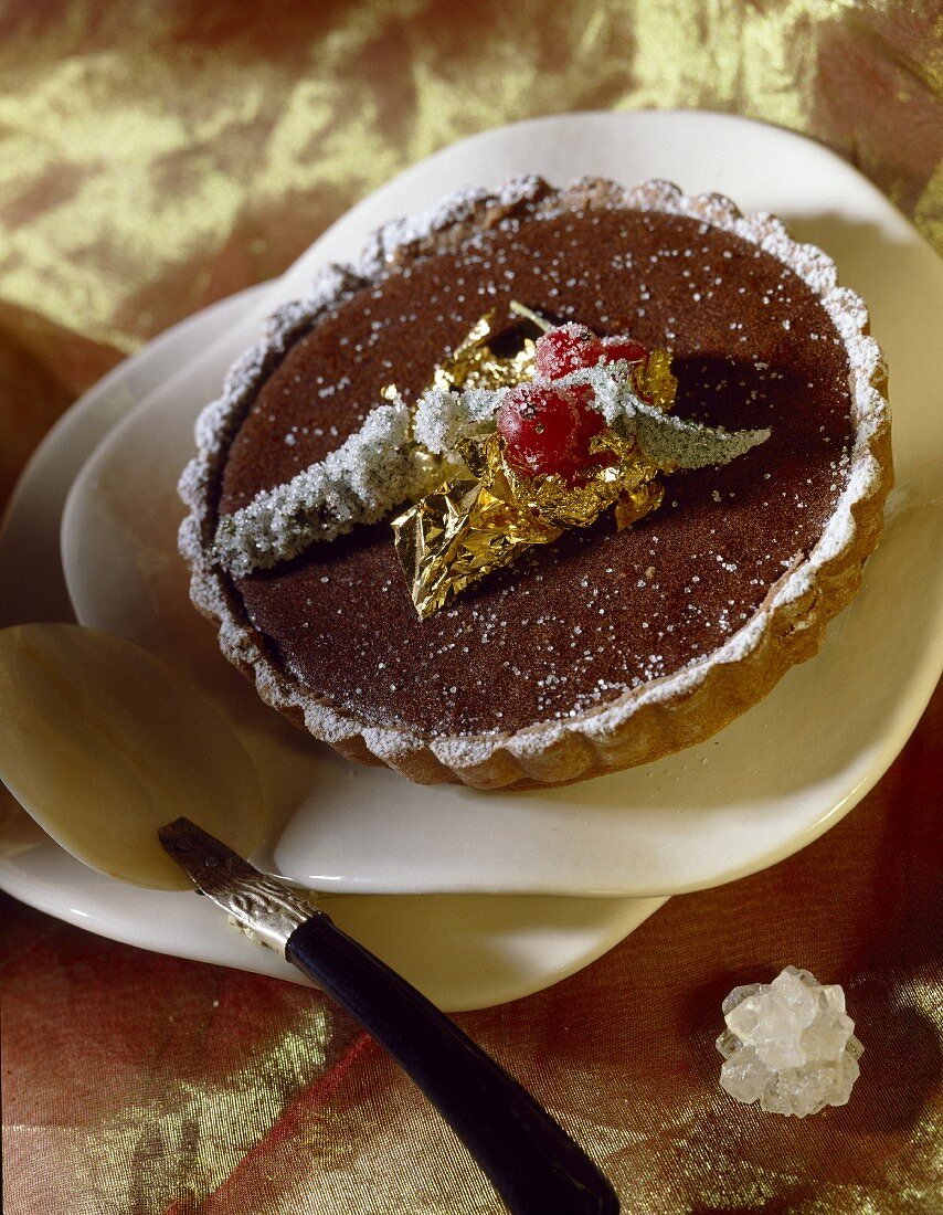 Chocolate tartlet decorated with a golden leaf