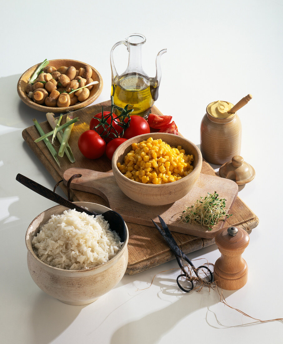 Stillleben mit Kochzutaten: Reis, Mais, Sprossen, Tomaten, Champignons, Öl, Senf