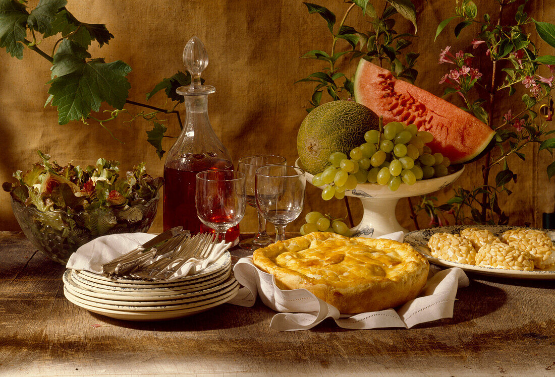 A buffet with mixed leaf salad, apple pie, a fruit bowl and wine