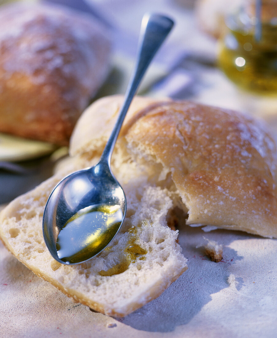 Löffel mit Olivenöl auf einem Brötchen