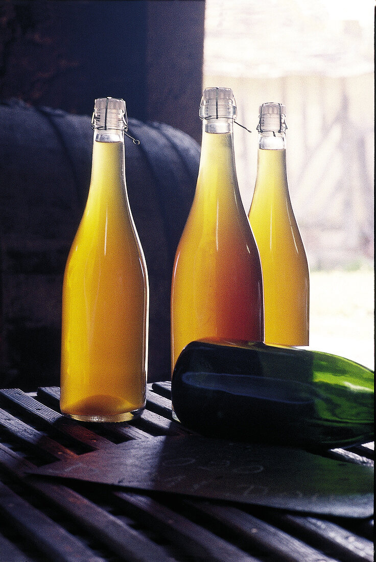 Flaschen mit Cidre, Holzfass im Hintergrund