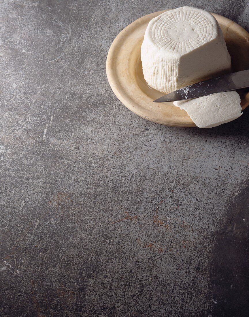 Angeschnittener Brocciu (Käsespezialität aus Korsika) mit Messer auf Steingutteller