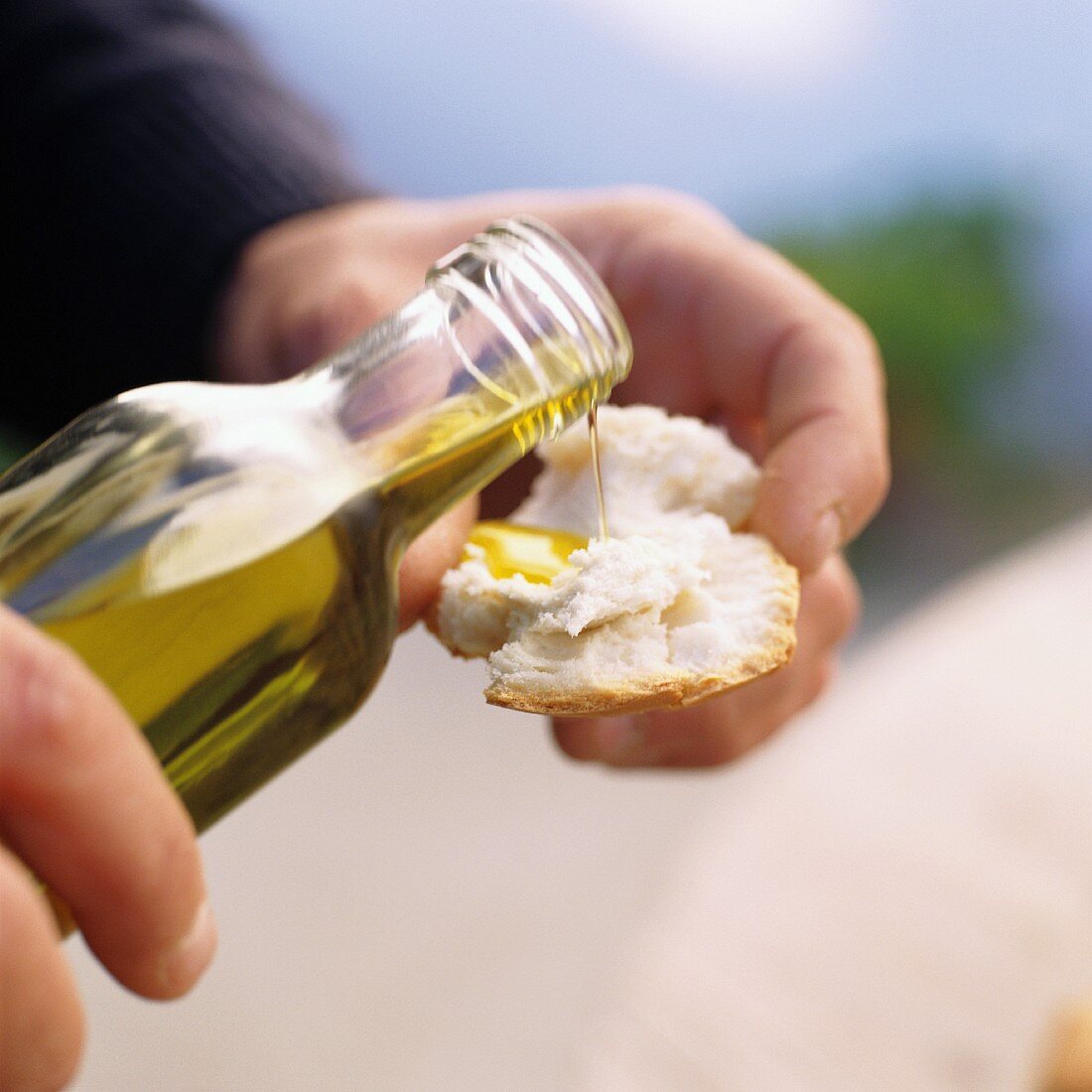 hands pouring olive oil onto bread