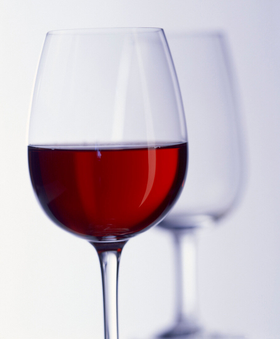 Ein Glas Rotwein, ein leeres Glas im Hintergrund