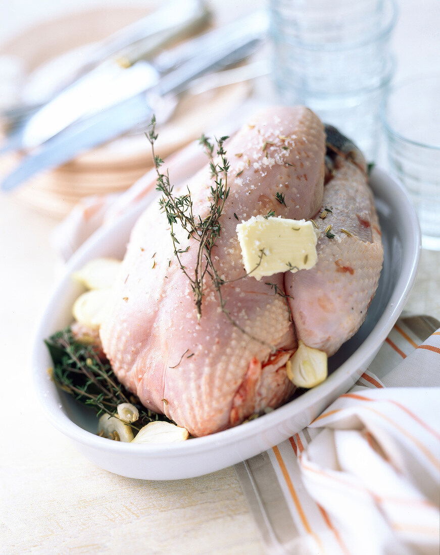 Mit Knoblauch, Kräutern und Butter vorbereitetes rohes Hähnchen in einer Backform