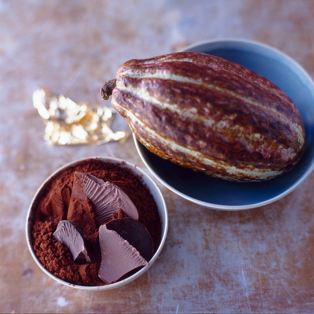 Kakaofrucht, Kakaopulver und Schokolade in Schälchen