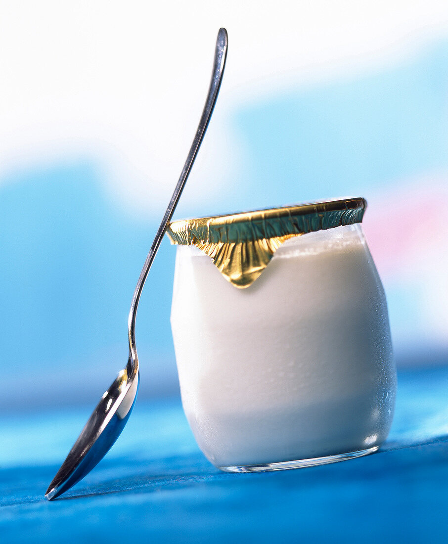 Ein ungeöffnetes Glas Naturjoghurt mit Löffel