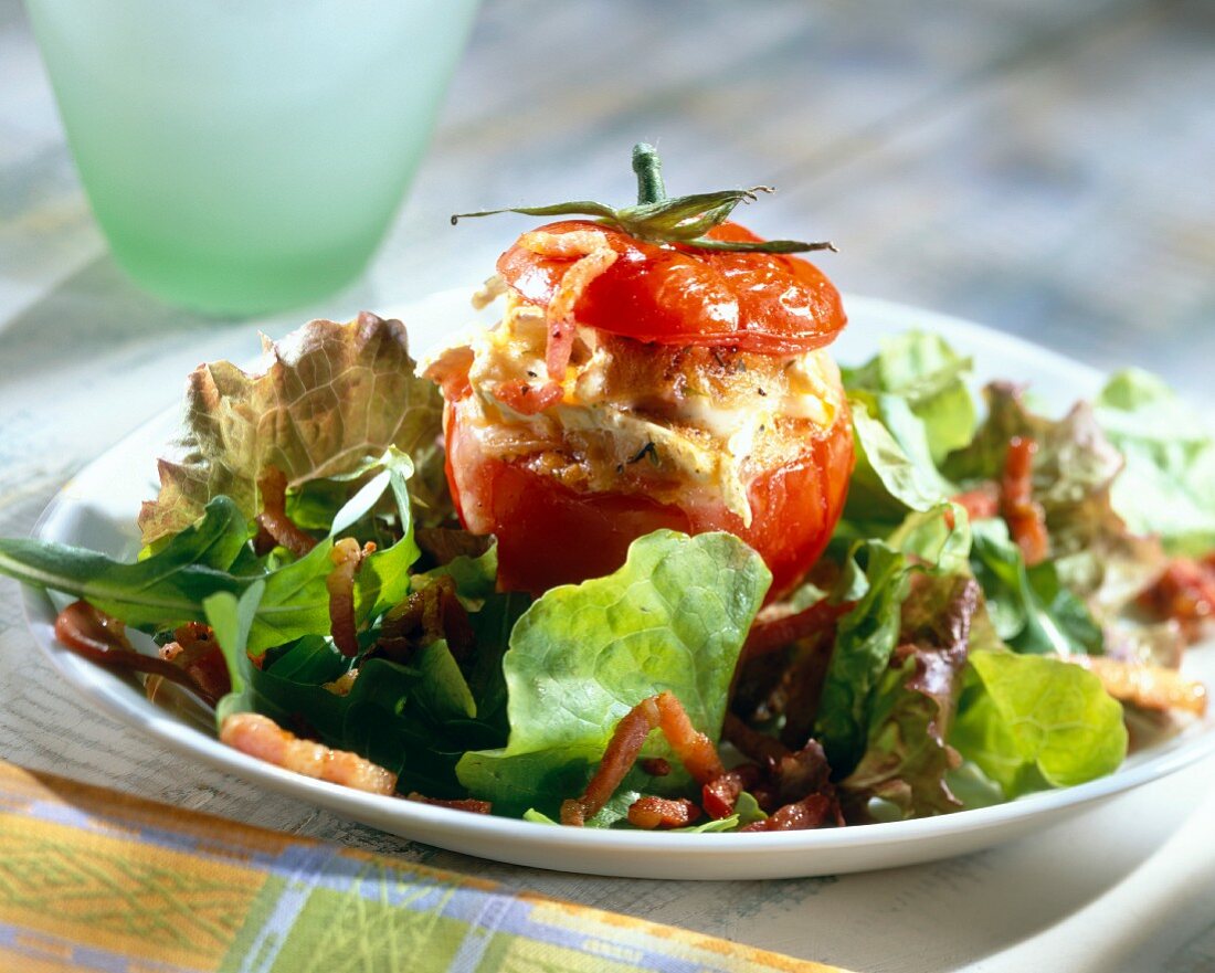 Mit Chaource-Käse gefüllte Tomate auf Salat mit Baconstreifen