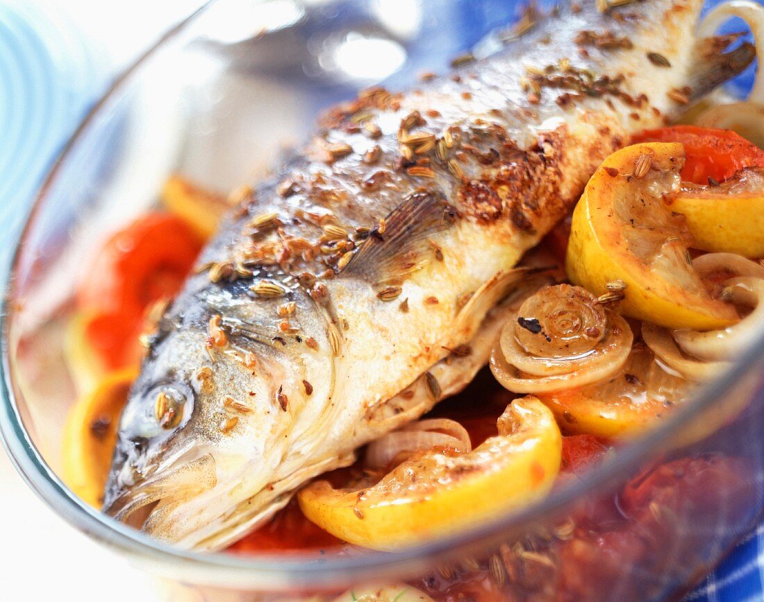 Baked bass with lemon, onions and tomatoes