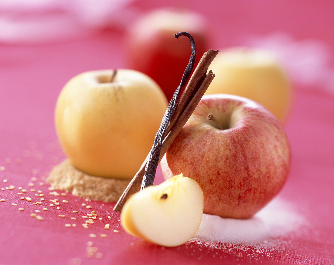 Stillleben mit frischen Äpfeln auf Zucker, Vanilleschote und Zimtstange